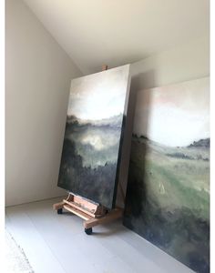 an easel sitting in front of two paintings