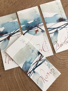 four pieces of paper with blue and red ink on them sitting on top of a wooden table