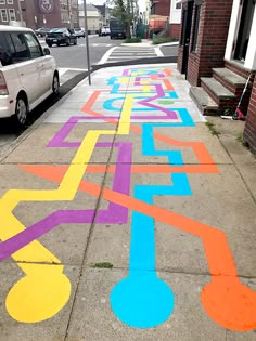 the sidewalk has been painted with different colors and shapes, including letters that spell out