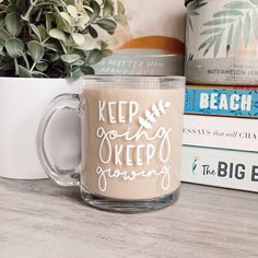 a coffee mug sitting on top of a table next to books and a potted plant