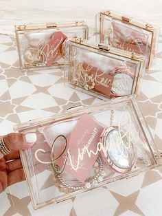 three clear acrylic boxes with personalized items in them on a patterned tablecloth