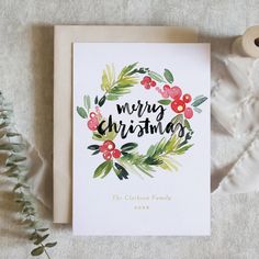 a card with the words merry christmas written on it next to a sprig of greenery