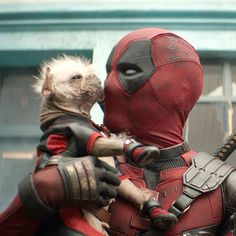 two deadpool characters are hugging each other in front of a building and one is wearing a costume