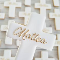 a white cross with the word mater written in gold on it, surrounded by cookies