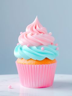 a cupcake with blue and pink frosting sitting on top of a white table