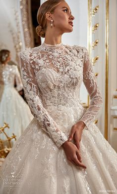 a woman in a wedding dress is looking at something on the mirror and she has her hands behind her back