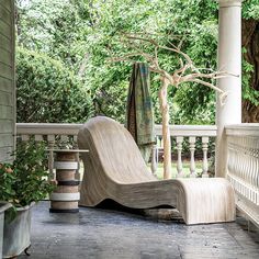 a wooden chair sitting on top of a porch next to a potted planter