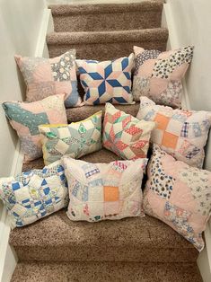 a bunch of pillows that are on the stairs in front of a stair case and some carpet