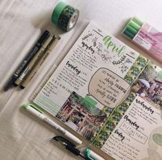 an open planner with pens and markers on it next to some other items that are sitting on a table