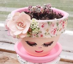 a potted planter with flowers and eyelashes on it sitting on a window sill