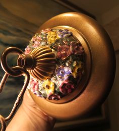 a close up of a person's hand holding a key with flowers on it