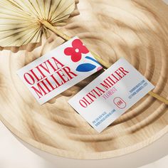 two business cards sitting on top of a wooden plate next to an open parasol