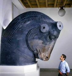 a man standing next to a large horse head