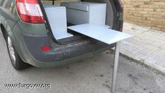 the back end of a car with an open hatchback and table in the trunk