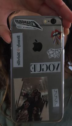 a person holding an iphone case with stickers on it