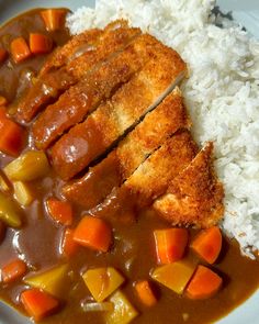 a white plate topped with rice and meat covered in gravy next to carrots