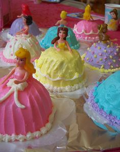 there are many princess cakes on the table with little figurines around them, all decorated and ready to be eaten