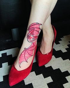 a woman wearing red shoes with a dragon tattoo on her left leg and right foot