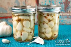 two mason jars filled with garlic on top of a blue table