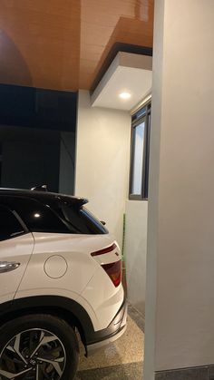 a white suv parked in front of a window next to a wall with a sign on it