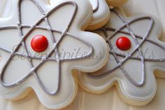 some cookies are decorated with white icing and red decorations on them, as well as an atomic symbol