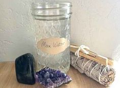 a glass jar filled with purple crystals next to a rock