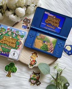 an animal crossing game sitting on top of a table next to flowers and stickers