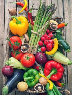 a crate filled with lots of different types of vegetables on top of a wooden table