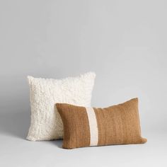 two brown and white pillows sitting next to each other