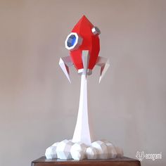 a red and white paper sculpture sitting on top of a wooden table