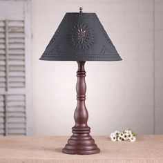 a wooden table with a lamp on top of it next to a vase and flowers