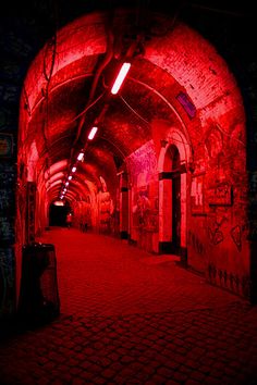 a tunnel with graffiti on the walls and red light coming from it's windows