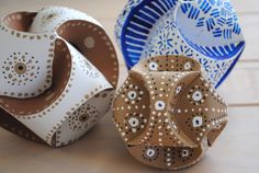 three ceramic bowls sitting on top of a wooden table next to each other and one is made out of paper