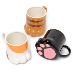 three coffee mugs with paws painted on the sides and one has a cat's paw