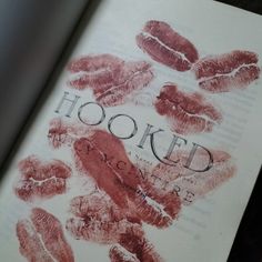 an open book with red imprints on the pages and words hooked to it's cover