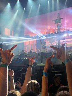 a group of people holding their hands up in front of a stage with lights on it