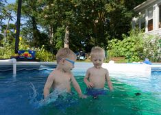 two young boys are playing in the pool