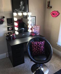 a black chair sitting in front of a desk with a mirror and lights on it