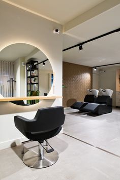 a modern living room with black chairs and a round mirror on the wall above it