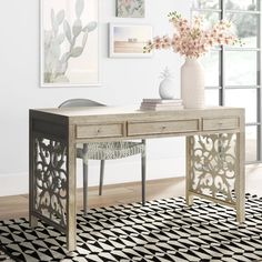 a white table sitting on top of a rug next to a vase filled with flowers