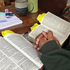 two people sitting at a table with open books in front of them, one holding the other's hand