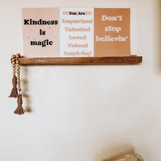 two posters are hanging on the wall above a wooden shelf with tasseled beads