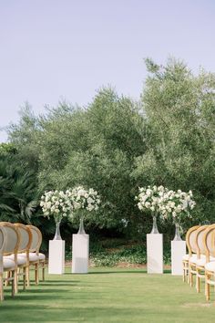 an outdoor ceremony setup with chairs and flowers in vases