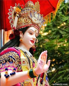 a woman dressed in an elaborate costume and holding her hand up to the side with both hands