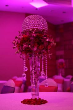 a tall vase with flowers on top of a table in a room filled with chairs