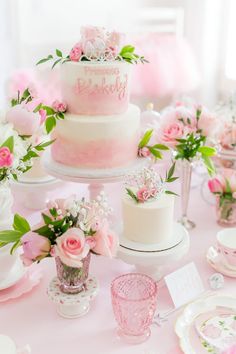 a three tiered wedding cake with pink flowers on top and two champagne glasses sitting next to it