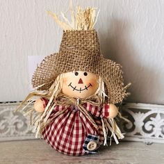 a scarecrow doll sitting on top of a wooden table next to a white wall