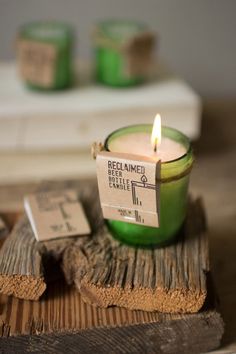 a green candle sitting on top of a piece of wood next to some small tags