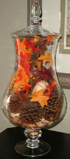 a glass vase filled with leaves and acorns