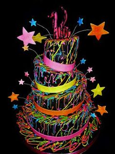 a multi - layered cake with stars and ribbons on the top is lit up at night